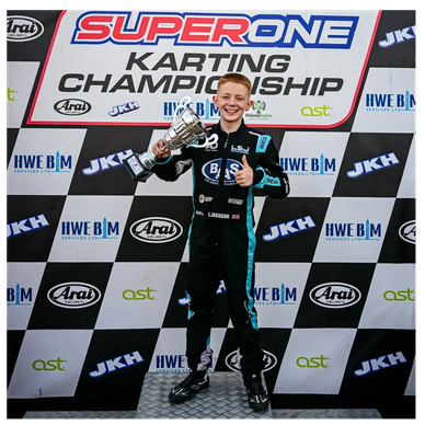 Young karting champion holding trophy and smiling.