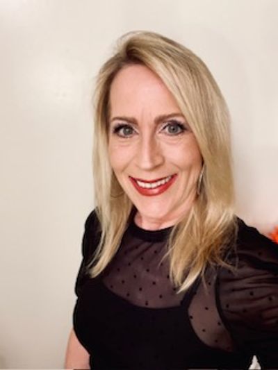 Smiling woman with blonde hair wearing a black top.