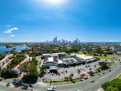 A wide aerial view of a city skyline with roads and buildings under a bright blue sky.