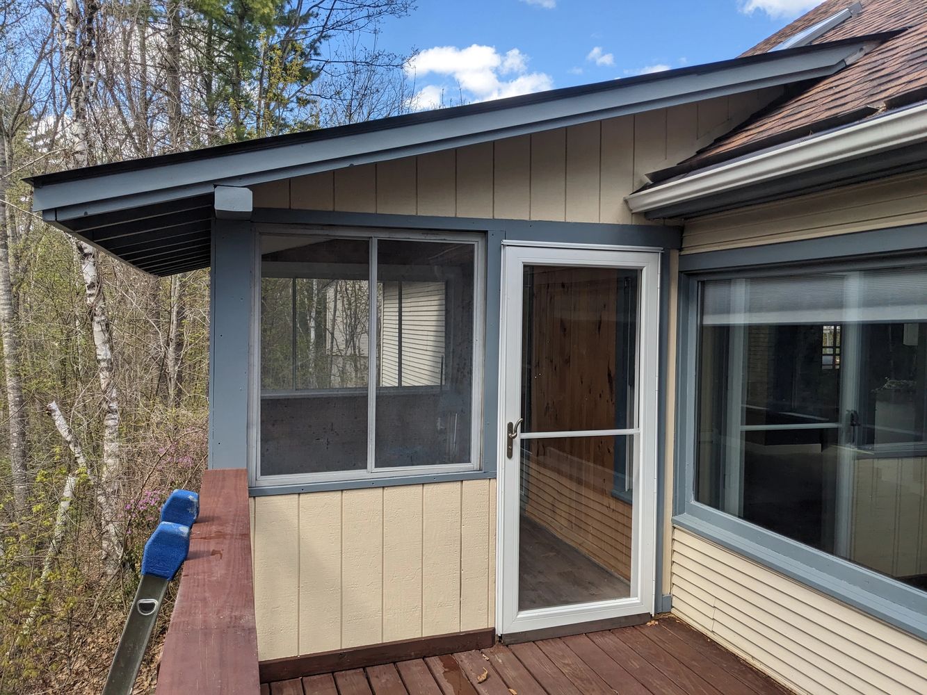 An outside porch wall, with fresh blue trim paint and new paint on the boards.
