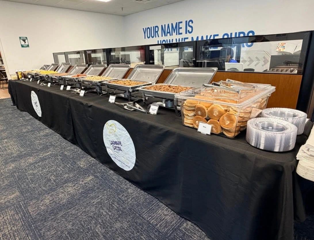 Buffet table with various food trays and bread.
