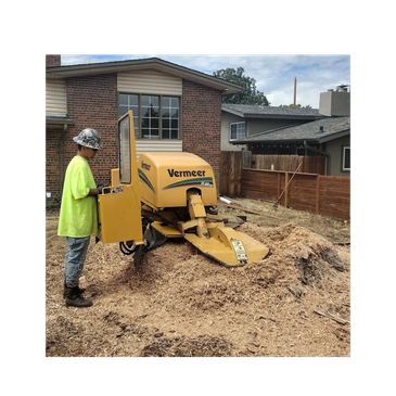 Worker operating a Vermeer wood chipper outside a house.