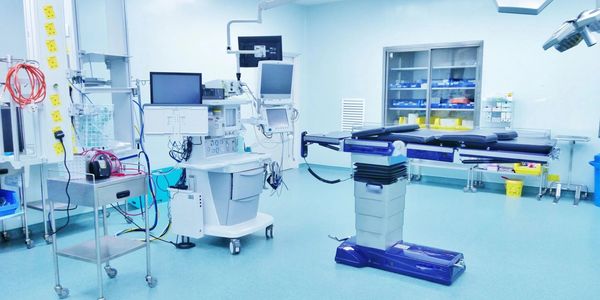 A clean, modern operating room equipped with medical monitors and an adjustable surgical table.