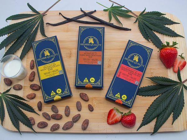 Three cannabis-infused chocolate bars with ingredients on a wooden board.