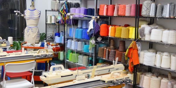 A colorful yarn shop with knitting machines and a dress form.