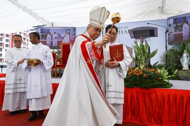 A bishop performing a religious blessing ceremony with assistants.