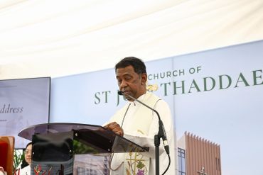 A priest speaking at a podium during a church event.