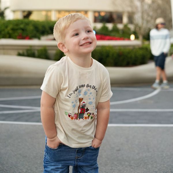 A smiling young boy with hands in pockets outdoors.