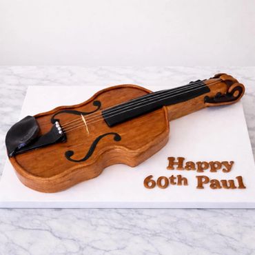 Violin-shaped cake with "Happy 60th Paul" message.