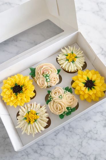 Box of six cupcakes decorated with intricate buttercream flowers in yellow and cream colors.
