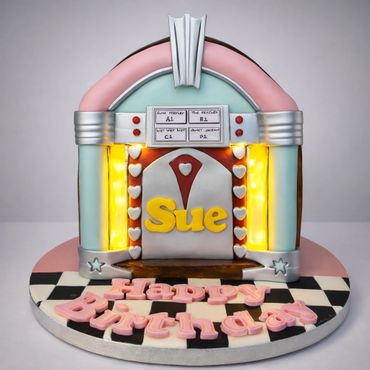 Jukebox-themed birthday cake with the name Sue and light accents.