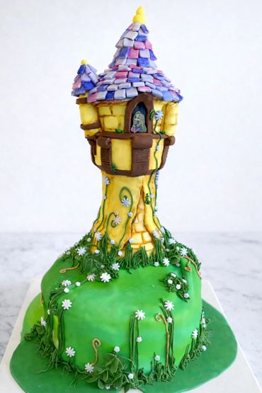 A colorful tower cake with purple roof tiles and green floral decorations.