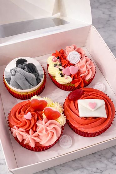 Box of four Valentine's Day cupcakes with romantic decorations and a photo topper.
