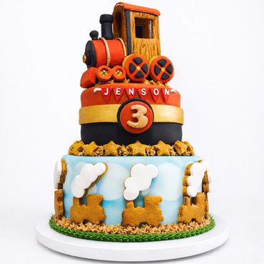 A vibrant two-tiered train-themed cake for Jenson's 3rd birthday.