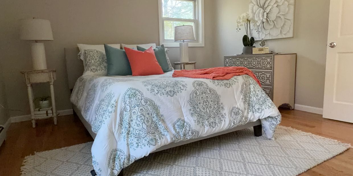 Cozy bedroom with patterned bedding, colorful pillows, and elegant decor.