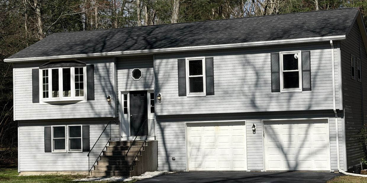Gray two-story house with black shutters and double garage doors.