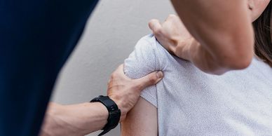 A person receiving a shoulder massage from another individual.