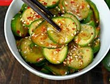 Bowl of seasoned cucumber salad with chopsticks.