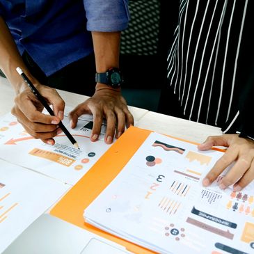 Two people reviewing charts and data on paper.