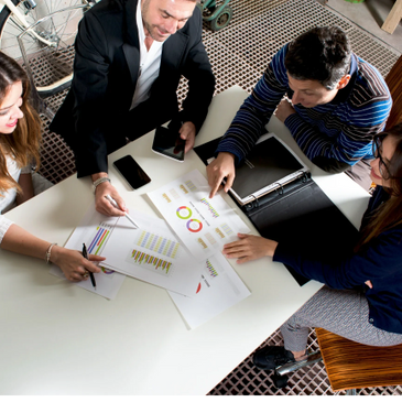 Four people collaborating over charts and graphs at a table.