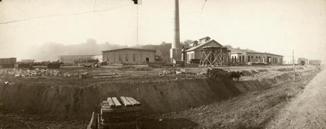 Old industrial site with several buildings and a tall chimney.