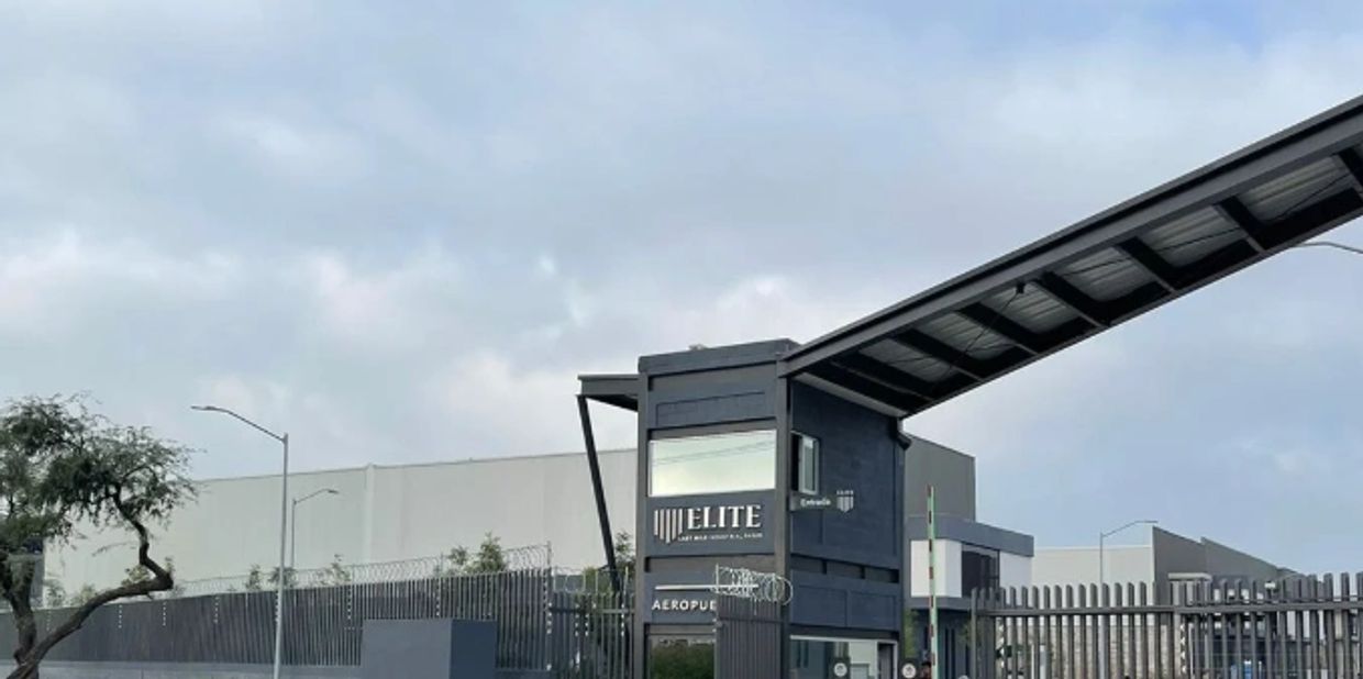 Security entrance of Elite logistics warehouse under a cloudy sky.