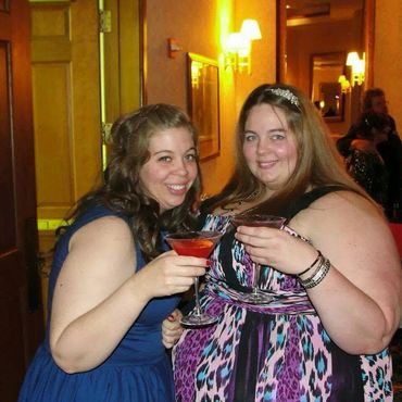Two women smiling and holding drinks at a party.
