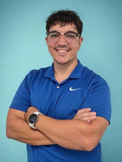 Smiling man in blue Nike polo with glasses and smartwatch.