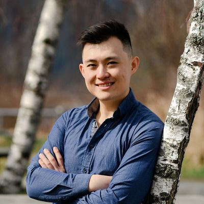 Smiling man leaning against a birch tree.