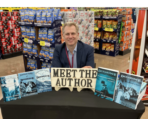 Author at a book signing event with a display of his books.