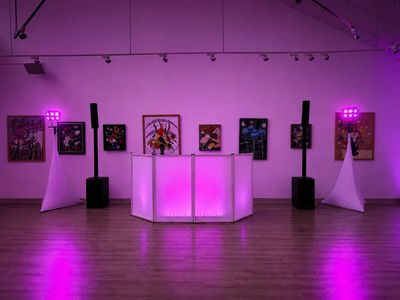 Art gallery with purple lighting and DJ setup.