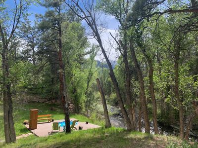 hot spring pool on deck with chairs next to Chalk Creek and trees in foreground