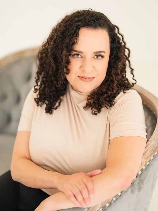 Photo of woman seated on a velvet sofa.