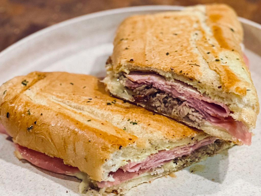 Diagonally cut cuban sandwich showing the layers of ham, salami, and pork. 