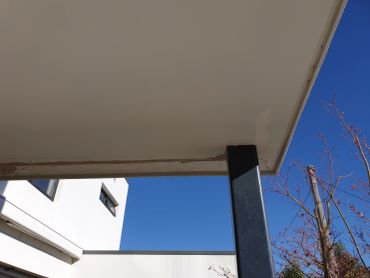 Modern building corner with blue sky and trees.