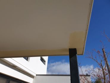 Stained ceiling on black pillar under blue sky.