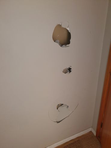 Three holes in a white interior wall.