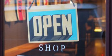 Open sign in a shop window, representing vacant storefront activation on a main street.