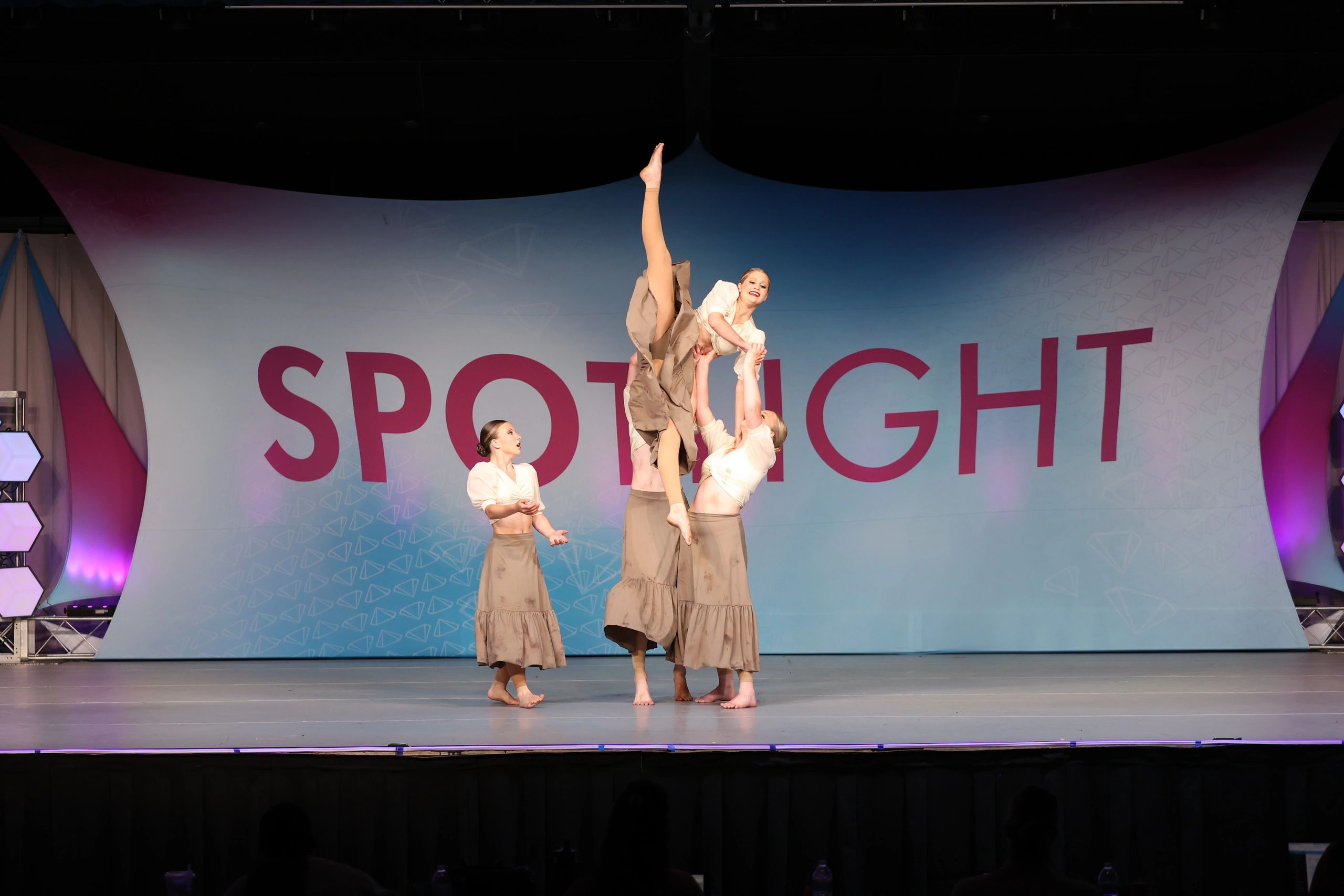 Four dancers perform a lift at a dance competition.