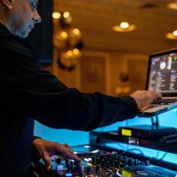 Person using a laptop with music software in a dimly lit room.