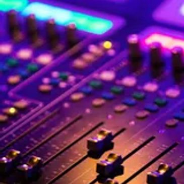 Close-up of a sound mixing console with colorful lighting.