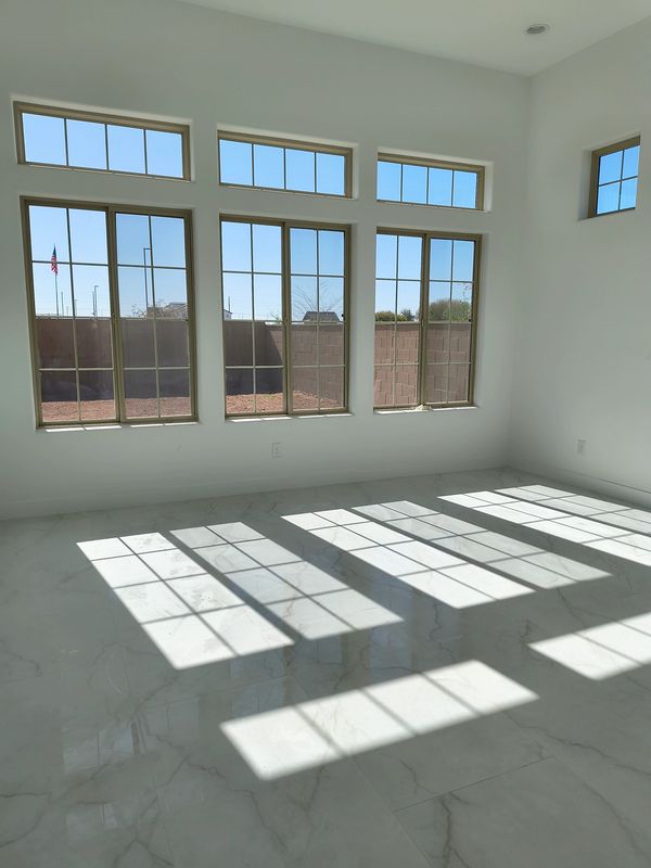 Sunlight streams through large windows onto a glossy marble floor in a bright, empty room.