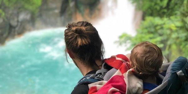 Niño y su papa observando una de las maravillas del mundo, una catarata de agua azul