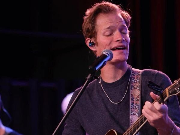 Man singing and playing guitar on stage.