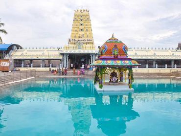 A colorful temple structure in the middle of a large blue water tank.