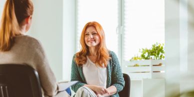 Two women engaged in a friendly conversation in a bright room.