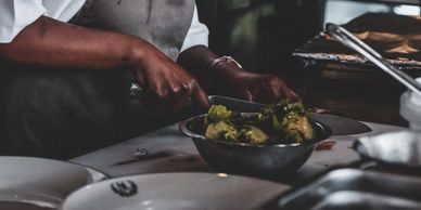 A person chopping vegetables and a bowl of vegetables on the surface