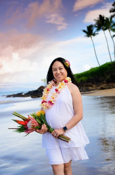 Maui pregnant woman holding flowers.
