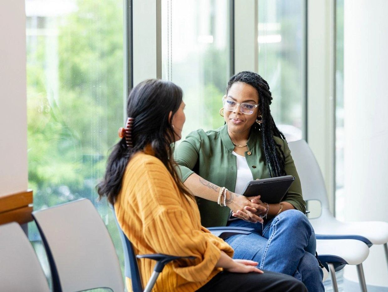 Two women engaged in a conversation indoors.