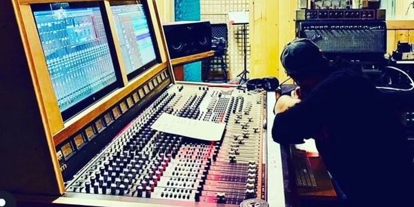 Person working at a large audio mixing console in a studio.